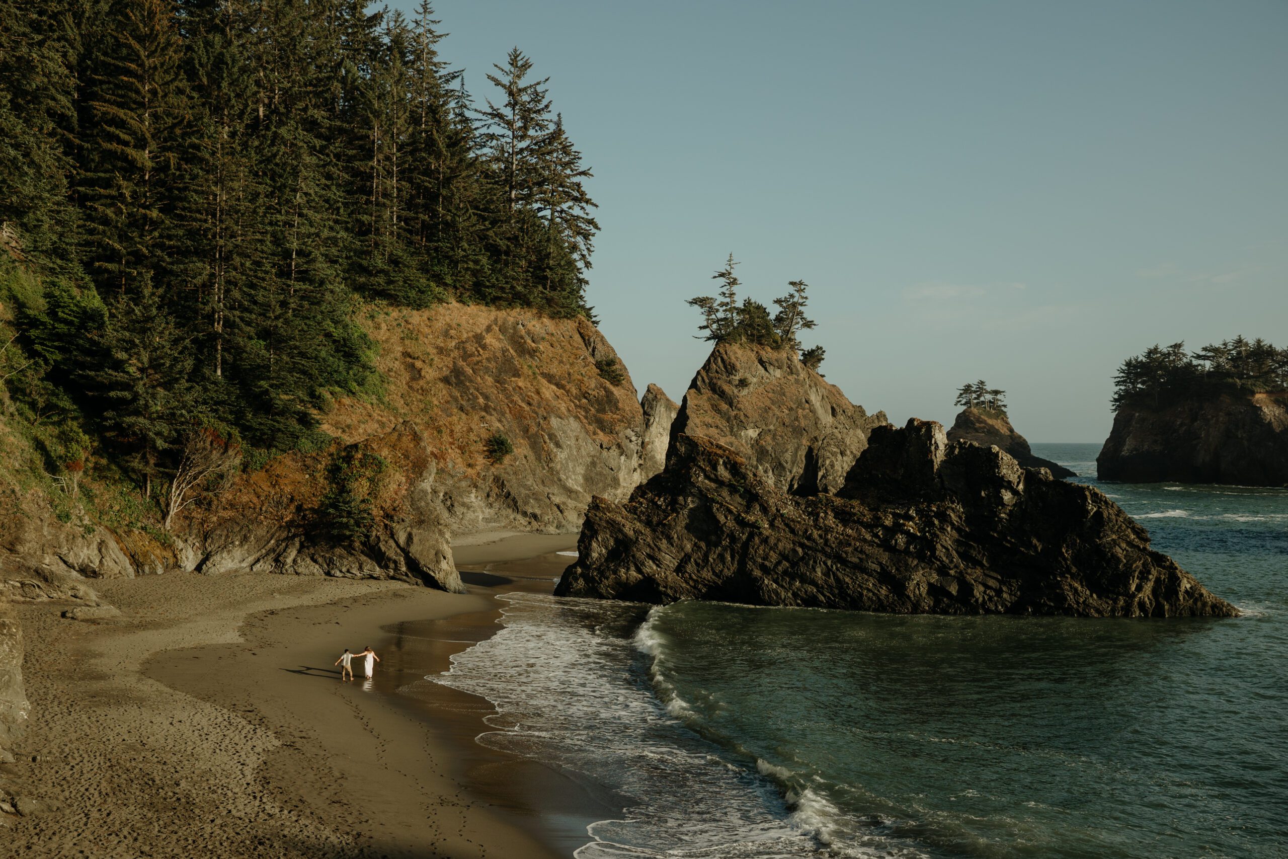 Couple running on Secret Beach in Samuel H Boardman, southern Oregon coast for engagement photos